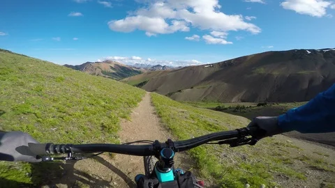 Cyclist Riding Down A Trail In A Meadow In The Mountains Video stock 115099403
