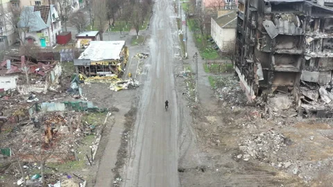 Cyclist riding in the middle of a russian-destroyed city 動画素材 200780953