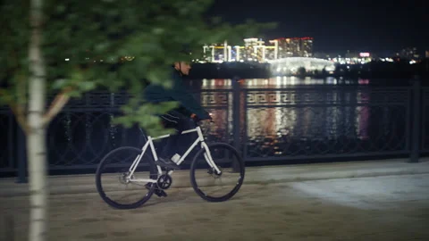 Cyclist riding at night along river bank 库存影片 345708474