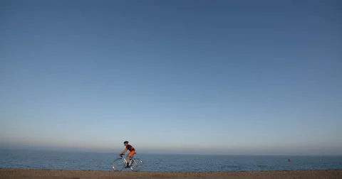 Cyclist riding with Ocean in background. Vídeo Stock 67647950