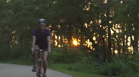 A cyclist riding on the road. The sun's rays fall nicely into the frame making Stock Footage 68972931