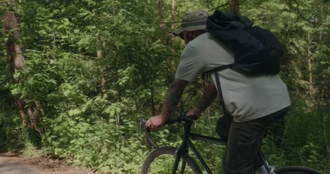 Cyclist riding through forest, side-rear view Stock Footage 311920188