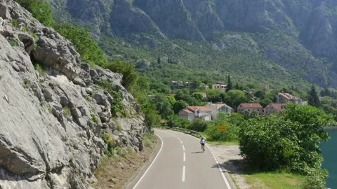 Cyclist on the road around mountains Stock Footage 223028562
