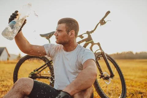 The cyclist sits in a meadow while resting from a strenuous ride on mountain  Stock Photos