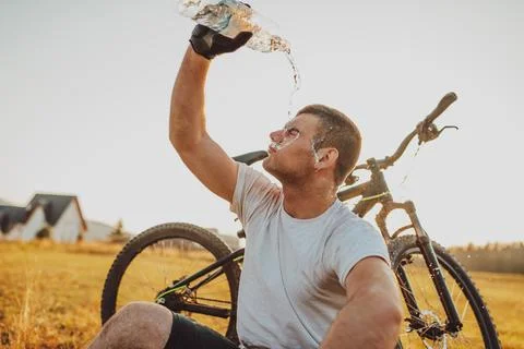 The cyclist sits in a meadow while resting from a strenuous ride on mountain  Stock-Fotos