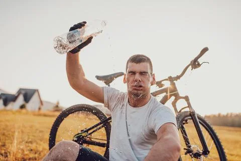 The cyclist sits in a meadow while resting from a strenuous ride on mountain  Stock Photos