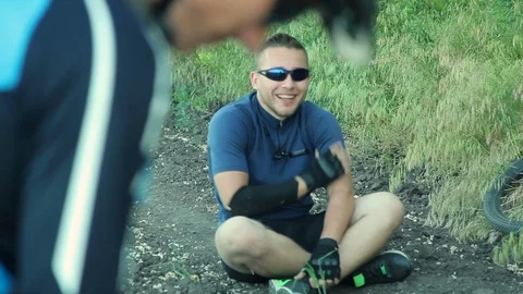 Cyclist sitting on ground Stock Footage 76594195