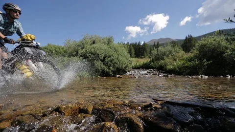 Cyclist splashes while riding through a shallow river Video stock 90820439