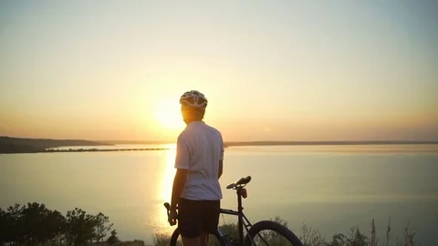 Cyclist stands with bike enjoy sunset coast rare view apid slow motion Stock Footage