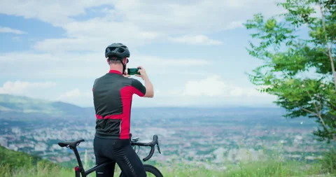 Cyclist takes a break on mountain road while enjoying view and capturing Stock Footage 339499449