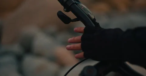 Cyclist Tracing Gloved Hand Across Mountain Bike Frame on Rocky Beach Stock Footage 347113520