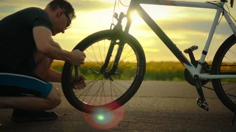 Cyclist. A traveler using a tool inflates a tire on the road. Cinematic shot Stock Footage 331307324