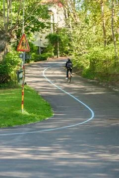 Cyclist on tree lined path with warning sign. Stock Photos