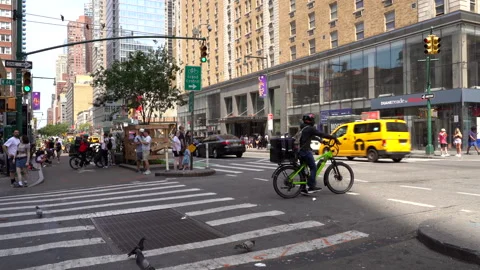 Cyclist Waiting at Traffic Light as Vehicles Pass Along 8th Avenue, NYC. Stock Footage 336290001