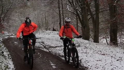 Cyclist waves before passing camera on snowy forest path. Stock Footage 83409396