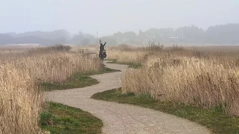 Cyclist waving happily on a winding path in a foggy landscape Video stock 339435171
