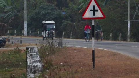 Cyclists and Auto Rickshaw Passing Road Intersection Sign in Rural Area Stock Footage 326761519