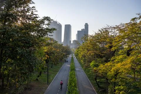 Cyclists and runners on tree lined path in benchakitti park bangkok Stock Photos