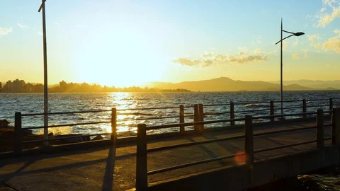 Cyclists on the Beira Mar Norte esplanade at sunset, Florianópolis, Santa Stock Footage 129326526