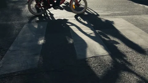 Cyclists crossing crosswalk casting long shadows Stock Footage 306581881