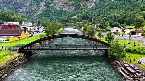 Cyclists crossing a river bridge in the beautiful village of Flam, Norway Stock Footage 341540400