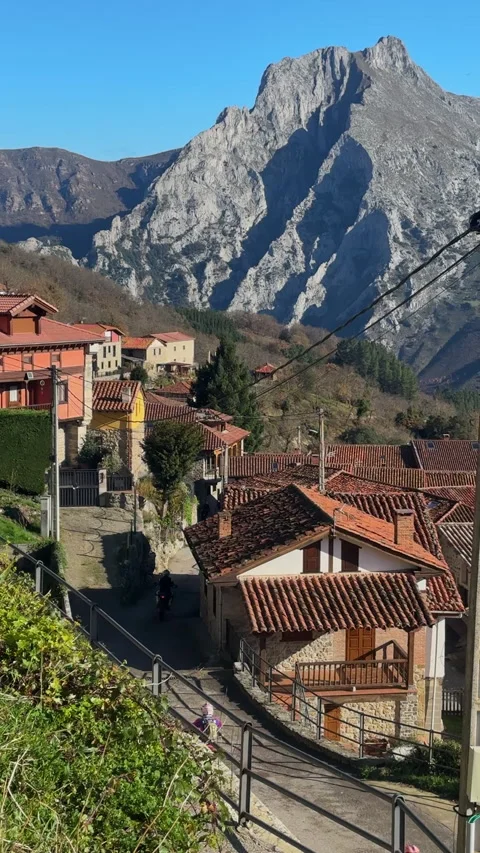 Cyclists descending mountain road through village in Picos de Europa 库存影片 339215705
