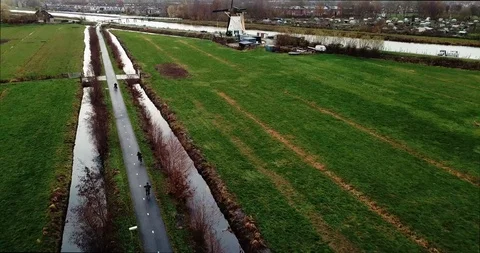 Cyclists in field next to windmill Video stock 101141291