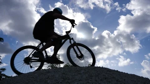 Cyclists Over Hilltop Clouds Silhouetted Stock Footage 203308312