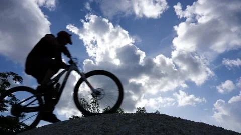 Cyclists Over Hilltop Clouds Silhouetted Stock Footage 203308599