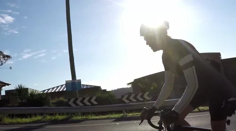 Cyclists pass as one rides up a hill slow motion Vídeo Stock 54939301