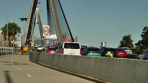 Cyclists pass vehicles using Anzac bridge in Sydney Australia slow motion Stock Footage 269608393