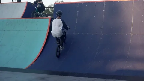 Cyclists perform a trick on a springboard in a skate park Video stock 103244445