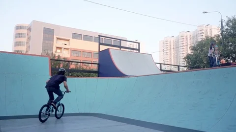 Cyclists practice joint stunt in skate park Stock Footage 103245794