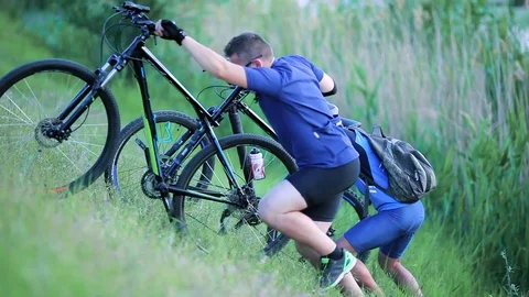 Cyclists pushing bikes up a hill Stock Footage 76593811