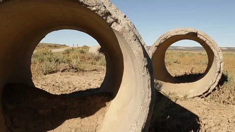 Cyclists ride behind tubes in a flat landscape Video stock 90822195