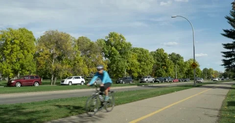 Cyclists ride on bike path on River Valley Road Stock Footage 55068212