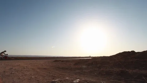 Cyclists ride in front of a low sun in the desert Egypt Video stock 90923541