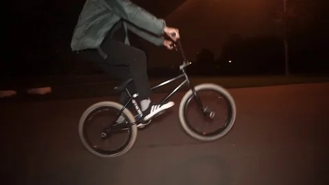 Cyclists rides at night on the sidewalk and perform tricks Video stock 103045014