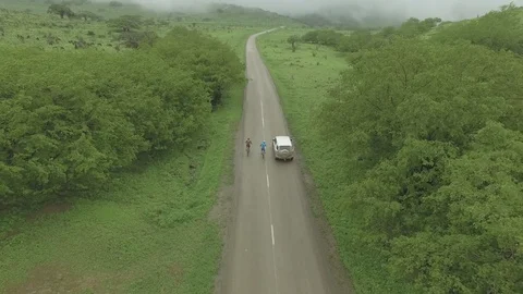 Cyclists riding along with an FJ Car Stock Footage