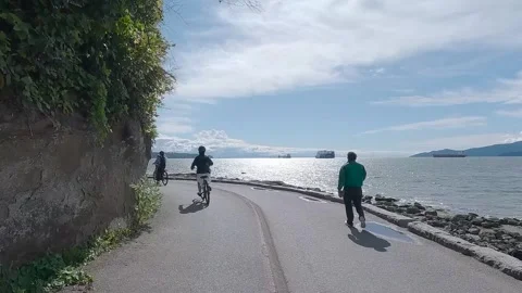 Cyclists Riding Along Stanley Park Seawall in Vancouver Stock Footage 337130277