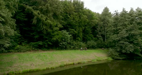 Cyclists Riding on Forest Path by Lake Shore with Green Trees Aerial Stockbeeldmateriaal 330109403