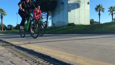 Cyclists riding in low angle view along a paved path in Batumi Stock Footage 345361741