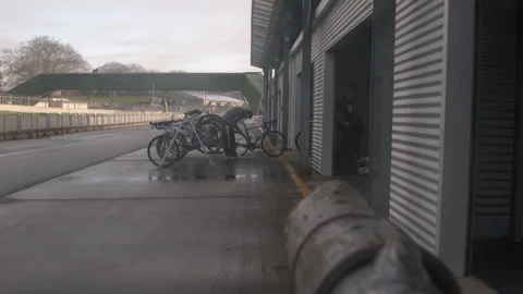 Cyclists take their bikes off the rack  before the race, in pit lane Stock Footage 247239797