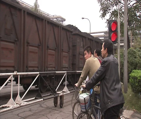 Cyclists wait for coal train to pass at railroad crossing Stock Footage 86744415