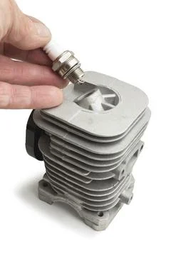 A cylinder for a two-stroke engine and a spark plug in the hand of a master Stock Photos