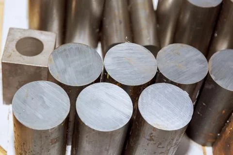 Cylindrical ingot of raw material is cut by a saw into pieces for processing  Stock Photos