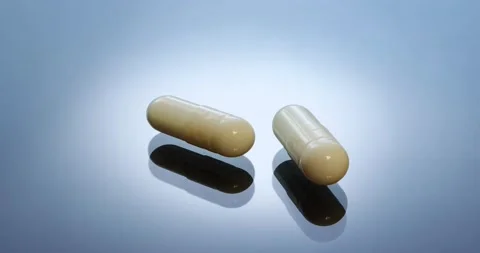 Cylindrical oval capsules with shadow on blue glass. Stock Footage 146536608