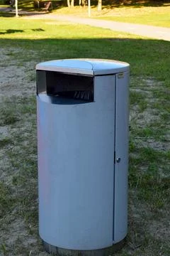 Cylindrical Trash Bin Next to a Bright Blue and Red Basketball Court in Tallinn Foto stock