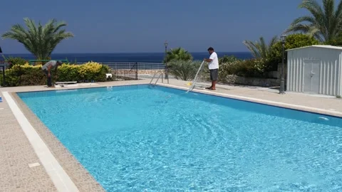 Cyprus, Larnaca, September 10, 2019. Two workers clean a private pool Stock Footage 130512803