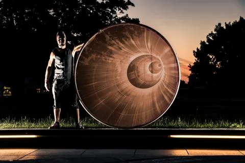 Cyr wheel performance session by young man at night. 스톡 사진